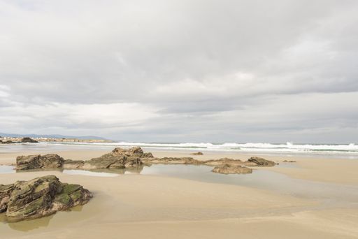 A small natural rock formations on a sandy As Catedrais beach on a gloomy day in Lugo, Spain