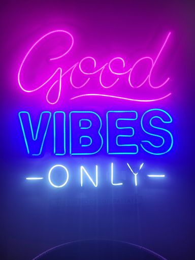 A vibrant neon sign featuring the phrase 'Good Vibes Only' in a combination of pink and blue tones
