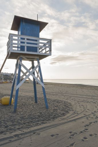 A vertical shot of a lifeguard tower on a beach under a cloudy sky in Malaga, Spain