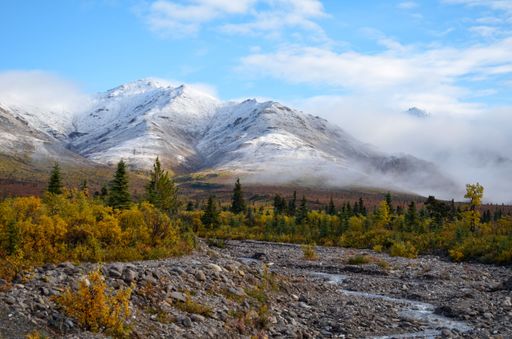 A majestic mountain landscape with a cloudy sky in the background, captured from a scenic view of an ancient riverbed