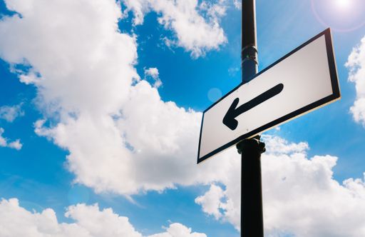 A low angle shot of a signboard of arrow showing the direction