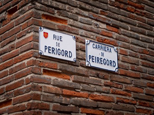 This image shows a red brick building wall with two signs attached