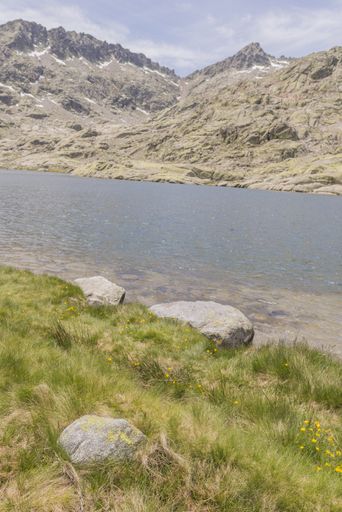 A vertical shot of a river surrounded by Gredos mountain range under a cloudy sky in Candeleda, Spain