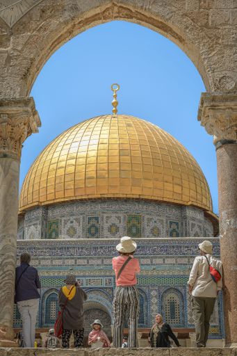 A group of people ascend a staircase towards the iconic and historically significant Dome of the Rock in Jerusalem