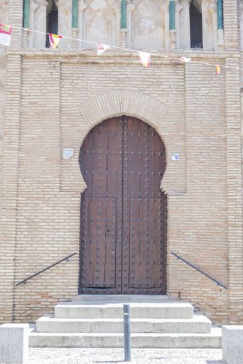 a vertical shot of a huge brown door with three stairs in Toledo Spain