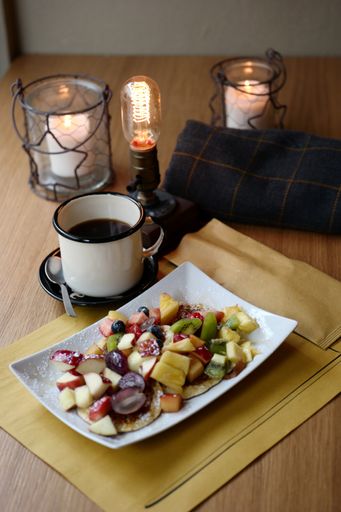 A vertical shot of coffee and fruit salat with two candles on the table