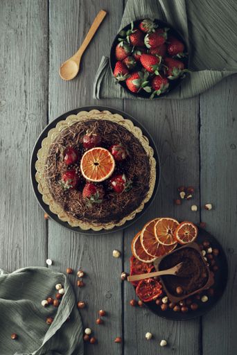 A vertical shot of a chocolate cake with dried fruits on a wooden surface