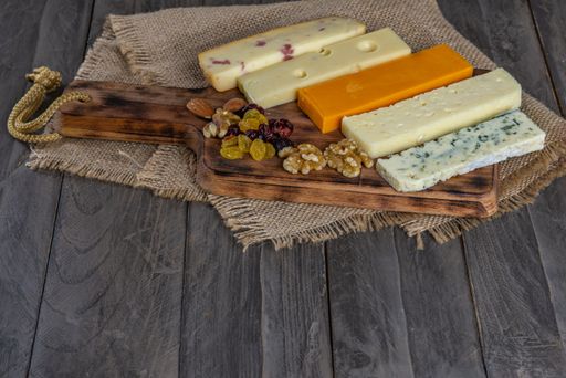 assorted cheese board with honey, nuts, blueberries and raspberries on wooden background
