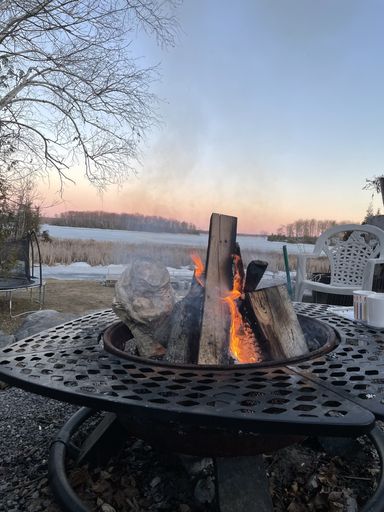A vertical shot of bonfire in a pit on the bay during sunset