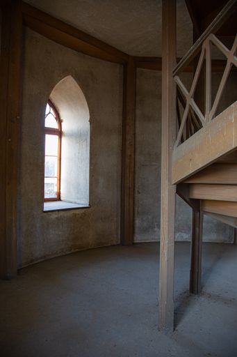 A vertical shot of an old building hall with wooden stairs and a window