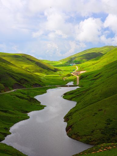 An aerial view of lush green hills and a tranquil river glistening in the sunlight