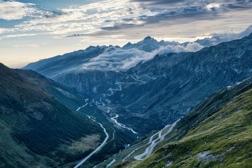 An aerial shot of serpentine roads through mountains and valleys on a sunny day