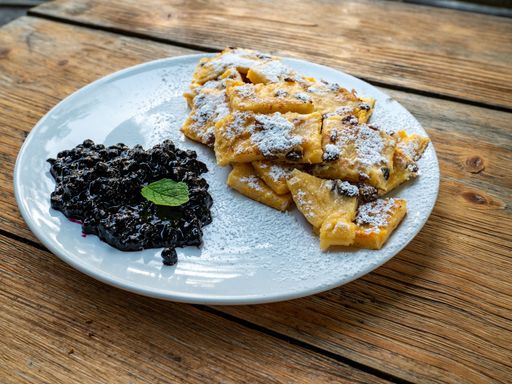 A close-up of a delicious plate of crepes with blueberry jam on a wooden table, ready to be enjoyed