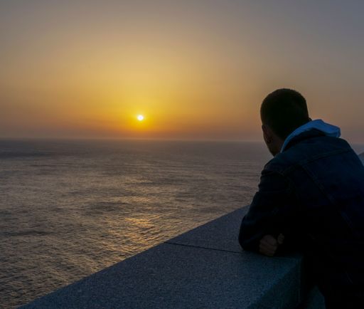 Man enjoying the sunset from Cape Ortegal, where you can see the sea and an orange sky typical of sunset. Cape Ortegal, A Coruna .Spain