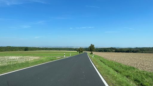 A scenic view of a deserted roadway in a green field