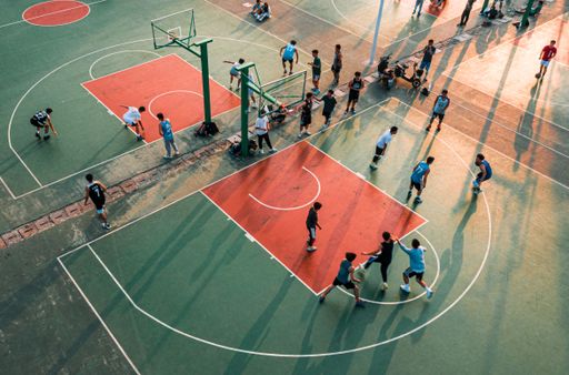 An aerial view of a basketball court, with a group of children playing a game of basketball