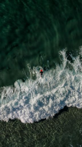 Aerial view of a surfer riding a surfboard in the ocean, seen from above