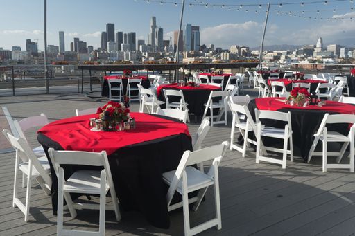 A picturesque outdoor dining area with a table set up on a balcony overlooking a city skyline of buildings
