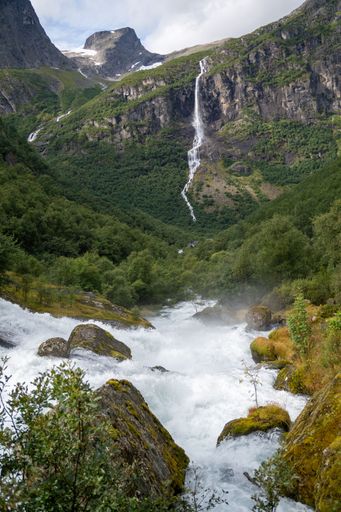 A scenic landscape featuring Volefossen waterfall surrounded by majestic mountains. Norway