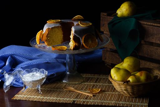 A closeup shot of a tasty orange cake, yogurt, and pear on the wooden table
