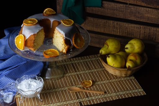 A closeup shot of a tasty orange cake, yogurt, and pear on the wooden table