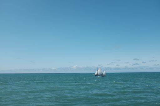 An aerial view of a majestic white sailboat sailing across the ocean's tranquil waters