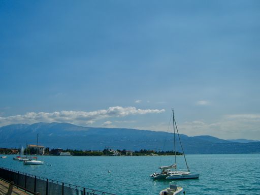 A stunning view of boats in Lake Garda with crystal clear water in Italy under a beautiful blue sky