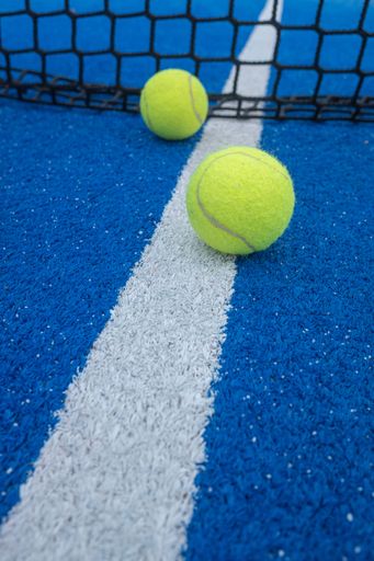 A professional blue tennis net stretched across the court with a line of tennis balls placed neatly