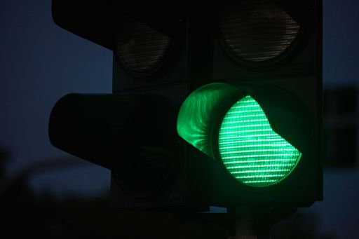 A close up of a green traffic signal light illuminated in the dark