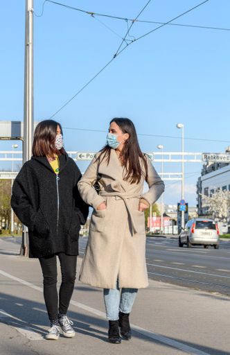 Female friends walking in city, wearing protective masks during corona virus epidemic.