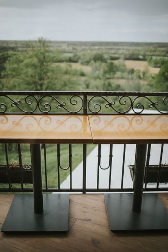 A vertical shallow focus shot of wooden tables on a balcony with a blurry forest in the background.