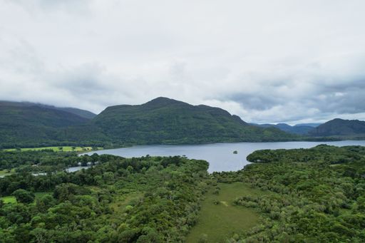 A scenic landscape view of a mountain range with a serene lake and rolling hills in Ireland, Kerry