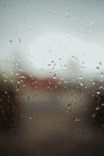 A vertical shot of window glass with raindrops on it