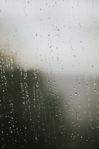 A vertical shot of water droplets on a window glass after the rain