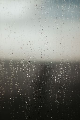A vertical shot of water droplets on a window glass after the rain