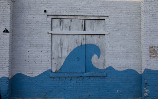 A close-up of a window with its shutter with a blue ocean wave painting