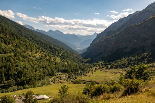 A scenic landscape featuring expansive green hills and mountain peaks in the distance