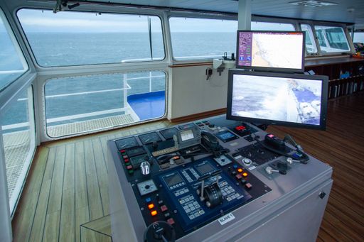 The center console in the wheelhouse of a ferry. There are a lot of buttons and computer screens designed for steering the ship