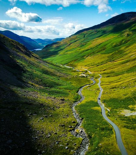 A scenic road winding through lush green hills in a valley