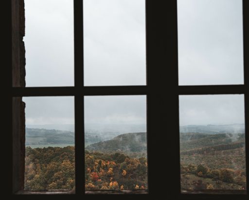 A beautiful view of high rocky mountains with greenery seen through the window