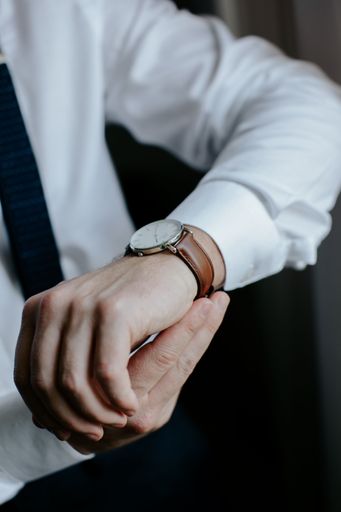 A closeup shot of a groom adjusting a wristwatch on his arm.