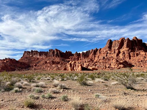 A majestic landscape of large red rocks against a cloudy blue sky