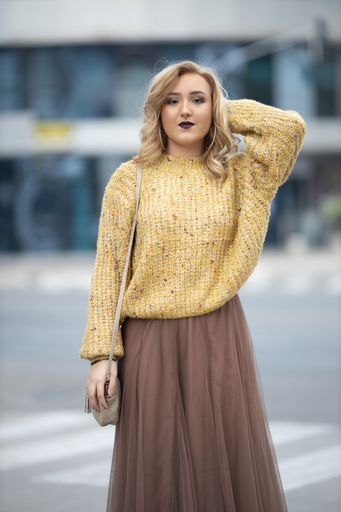 A vertical shot of a beautiful Caucasian female posing outdoors in a stylish outfit
