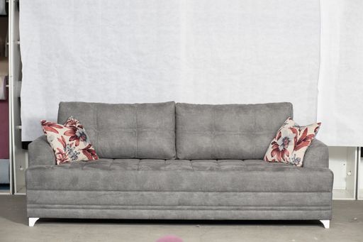 A closeup shot of a grey, modern couch with pillows in a room