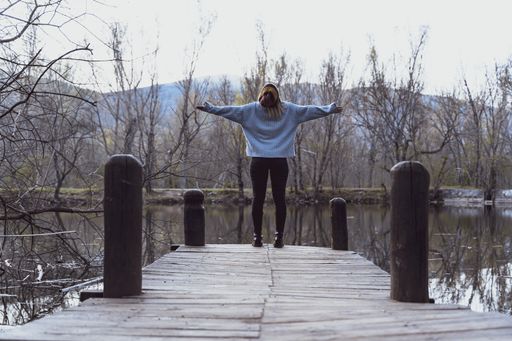 a young woman on a wooden pier at a lake - liberty concept