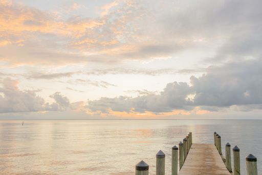 A closeup of a wooden dock stretching over a body of tranquil water at sunset in Fairhope