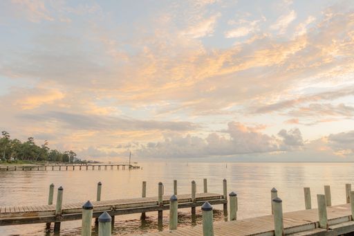 A closeup of a wooden dock stretching over a body of tranquil water at sunset in Fairhope