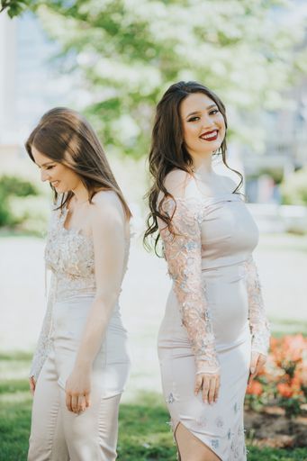 A vertical shot of two beautiful young Caucasian females posing outdoors in elegant clothing