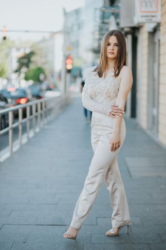 A vertical shot of a beautiful young Caucasian female posing outdoors in an elegant jumpsuit
