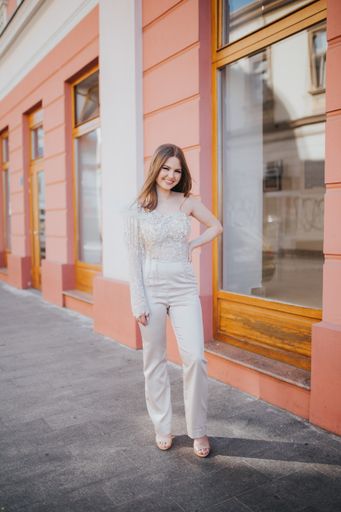 A vertical shot of a beautiful young Caucasian female posing outdoors in an elegant jumpsuit